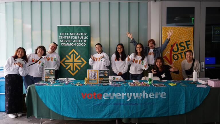 students stand in front of table that says vote everywhere