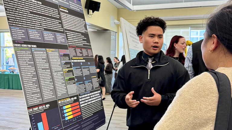 student explains his research at an event
