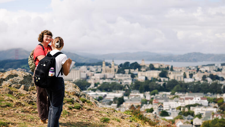 students stand on top of hill that overlooks san francisco