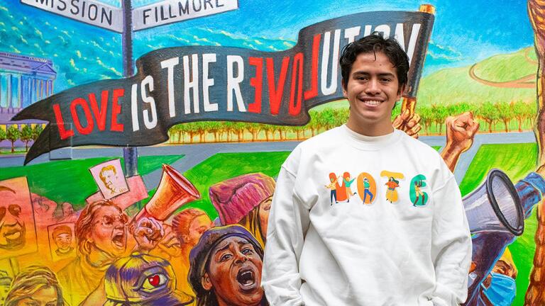 USF Votes team member stands in front of McCarthy mural