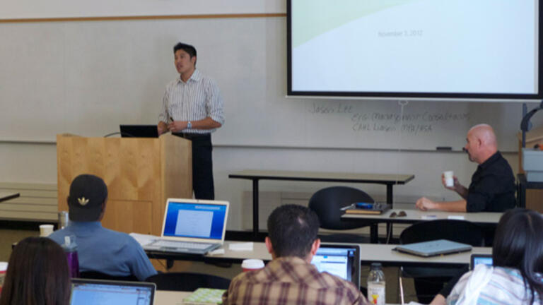 Professor stands behind podium in classroom