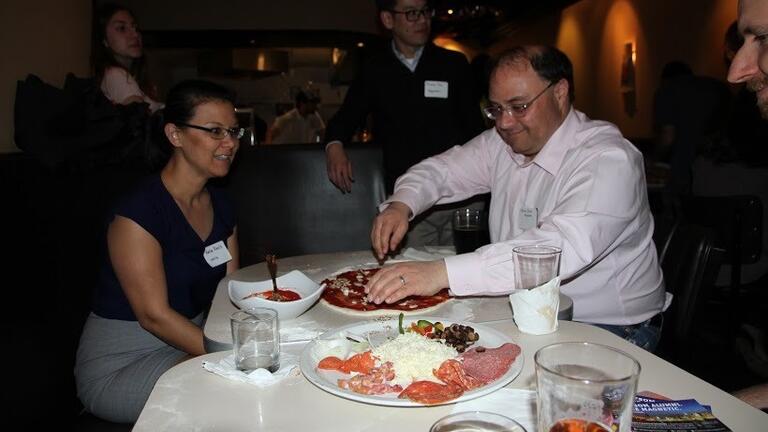 Person reaching for pizza at table