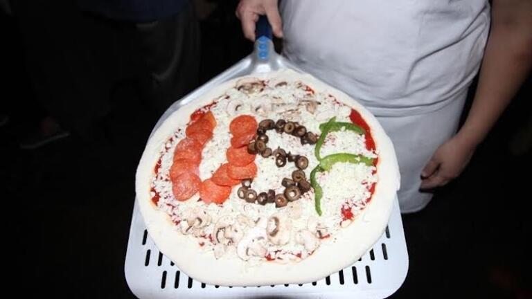 Pizza on pizza peel decorated with toppings that spell out "USF"