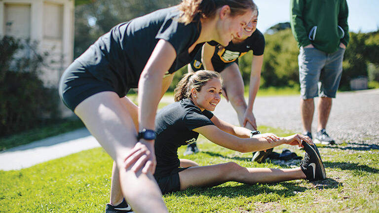 Women's cross country team members stretch