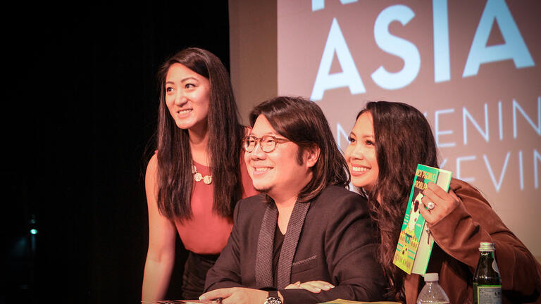 Author Kevin Kwan takes photos with students holding one of his novels