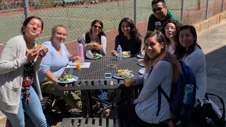 Students eat at a table outside. 