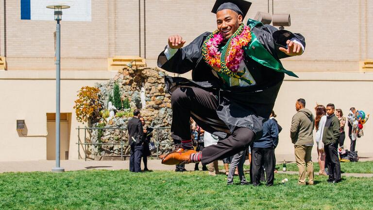 Graduate leaps in the air with joy at commencement
