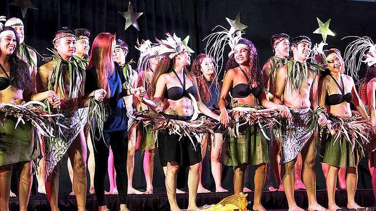Students stand and hold hands together on stage at Hui O Hawaii club's 43rd annual lu'au