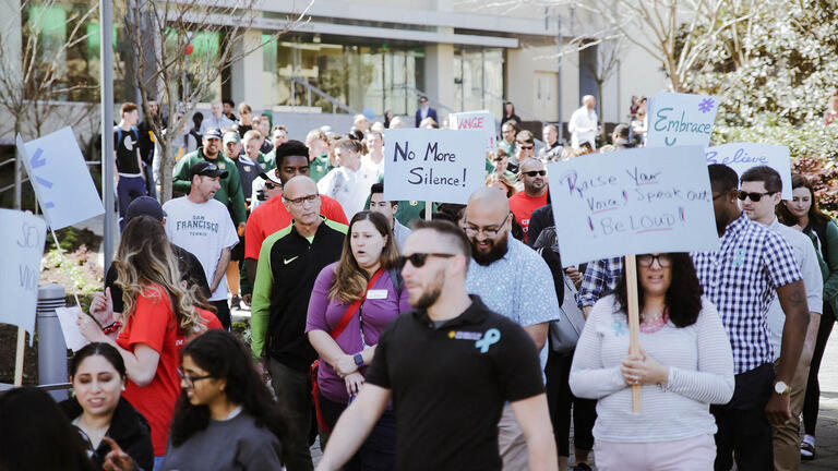 USF faculty, staff, and students holding signs and marching for Sexual Assault Awareness Month.