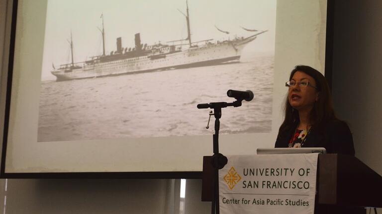 Speaker in front of a photo of a boat