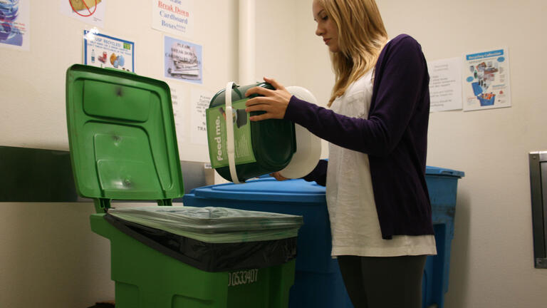 Sophomore Jolene Goldsmith, environmental studies major dumps bucket into compost bin as part of new program to encourage living green