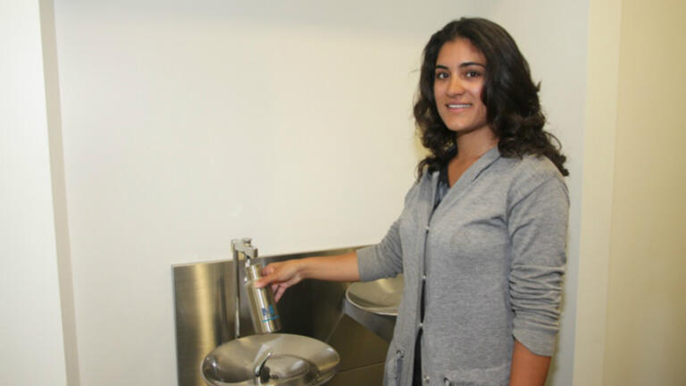 Sabeen Ahmad, co-chair of USF’s MBA Net Impact chapter, refills a Net Impact-branded water bottle