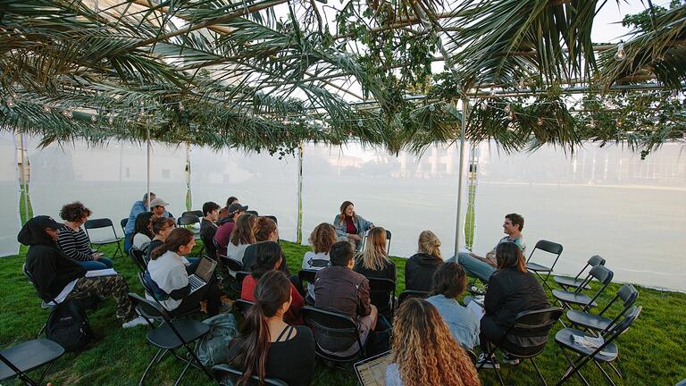 A group of about 20 gathered in the Sukkah, listening to a lecture