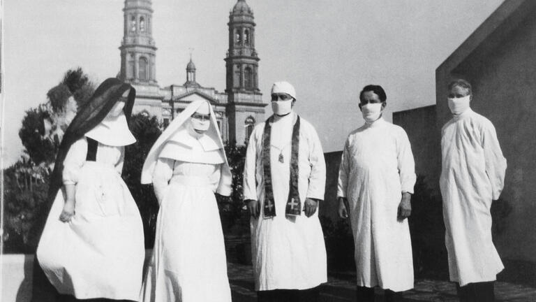 Priests and nuns wearing masks stand in front of St Ignatius Church.