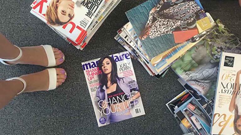 Ingrid Van Diest ('16), walking among stacks of fashion magazines