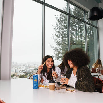 Two students chat at a table in the cafeteria