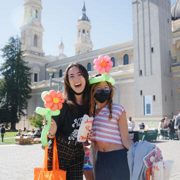 Two students at a fair in Gleeson Plaza with balloon flowers