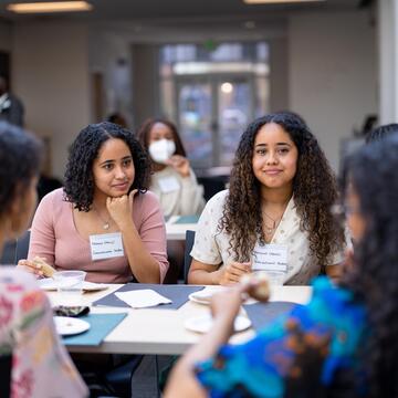 Students wearing name tags eat at a table