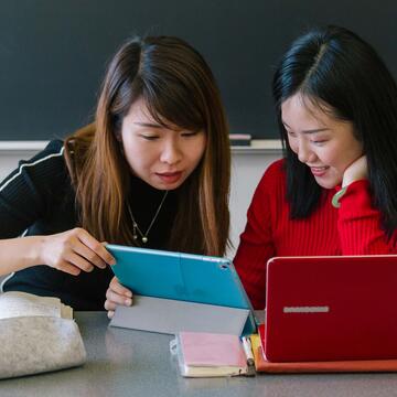 Two students look at a laptop in class.