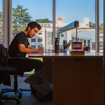 Student studies at a table in the library.