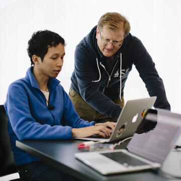 Student and instructor working on laptop.