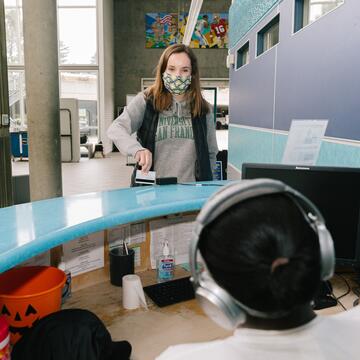 Front desk worker welcoming patron at Koret