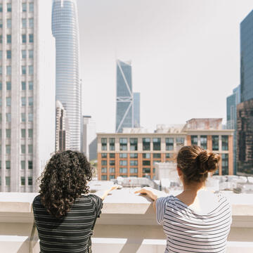 Students on a roof look at the city skyline.