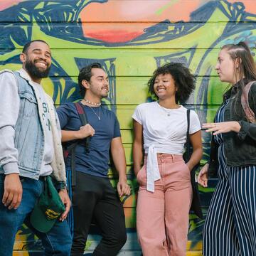 Students talk while standing in front of a mural in Haight Ashbury.