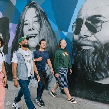 Students walk Haight Street past murals of Janice Joplin and Jerry Garcia.