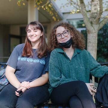 Two students sit on a bench.