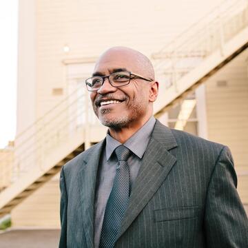 Dr. Joseph Marshall stands in front of a building smiling