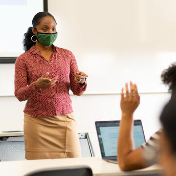 Teacher lectures at the front of a class.