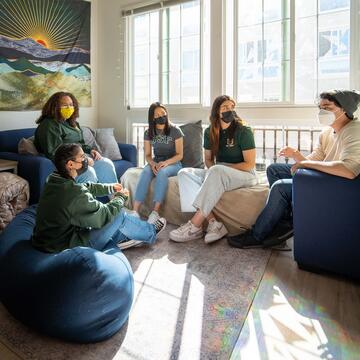 Several students chat in a dorm room.