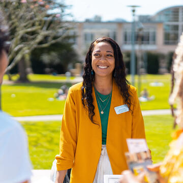 Staff member talks to two students on the lawn.