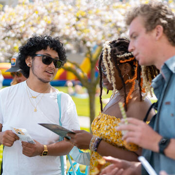 Students gather and talk at event on the lawn.