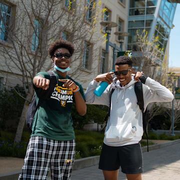 Two students laugh and point at the camera on USF campus.