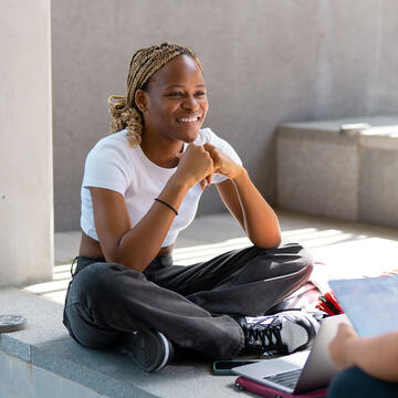 Two students talk while sitting on a wall at Lo Schiavo Science.