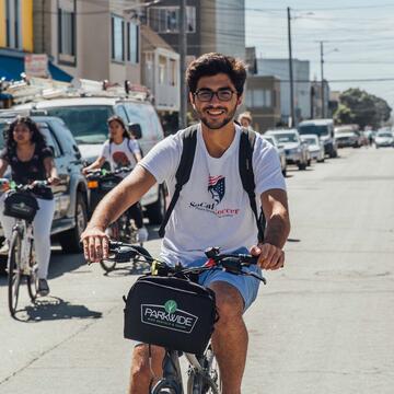 Student rides a bike down a busy street.