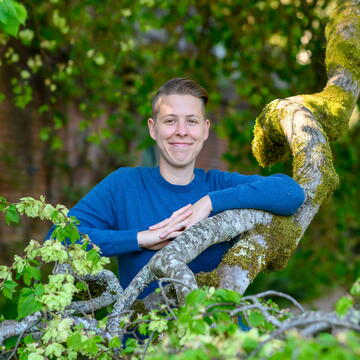 Student stands behind tree branch smiling