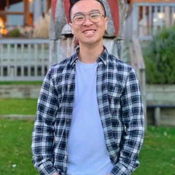 Evan Chan stands outside hands in pockets smiling