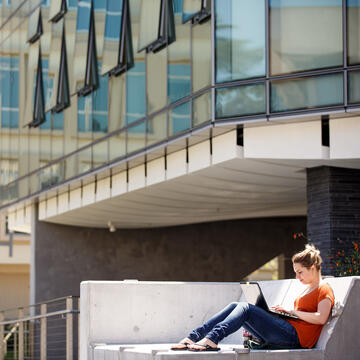 Student outside working on laptop.
