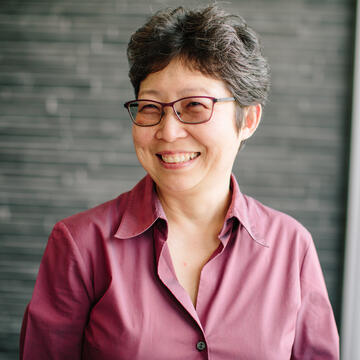 Professor poses in front of brick wall and smiles