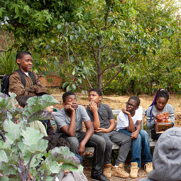 Professor instructs young students sitting outdoors