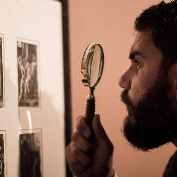 Student with magnifying class, looking at etchings