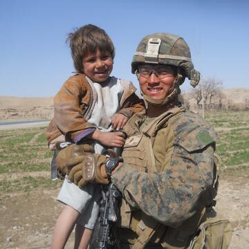 Person in combat fatigues holding child.