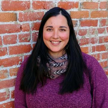 Amanda poses near a brick wall.