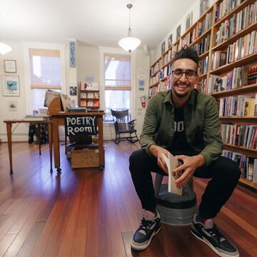 Man seated in a reading room, surrounded by books.