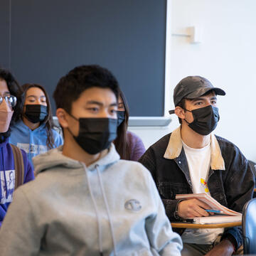 Students sit at desks listening to lecture