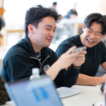 Students chat and laugh at a cafeteria table.