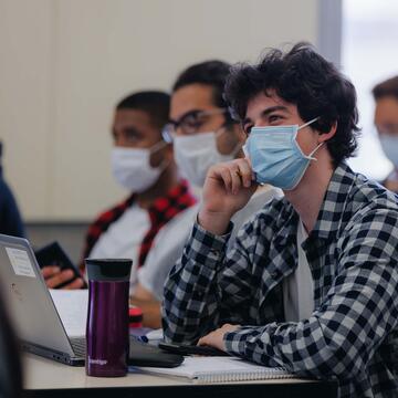 Student listens in class while resting head on their right hand